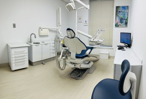 A dental chair placed in the middle of the room surrounded by medical equipment.